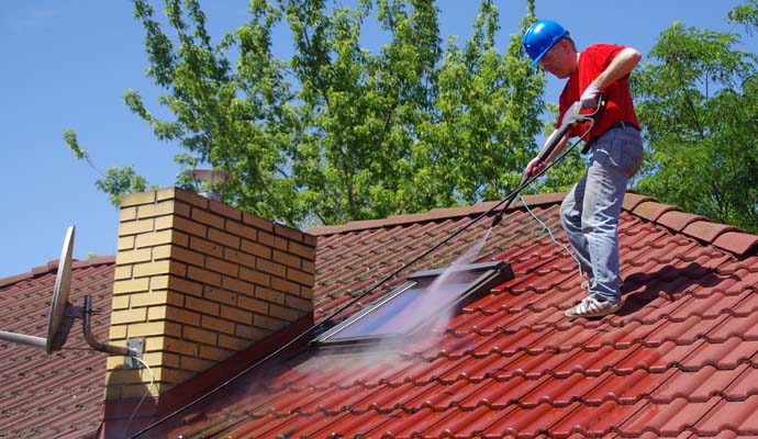Expert cleaning roof using soft washing equipment
