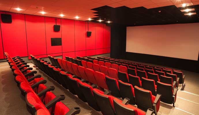 an empty clean movie theater with multiple rows of red seats