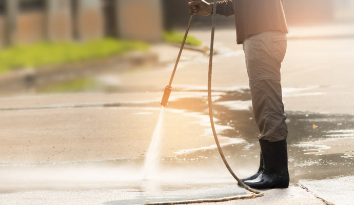 A person pressure washing a driveway