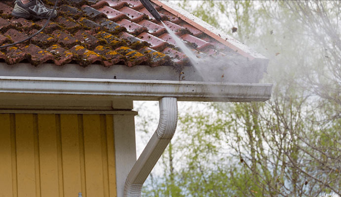 Pressure washing moss and debris from a roof and gutter