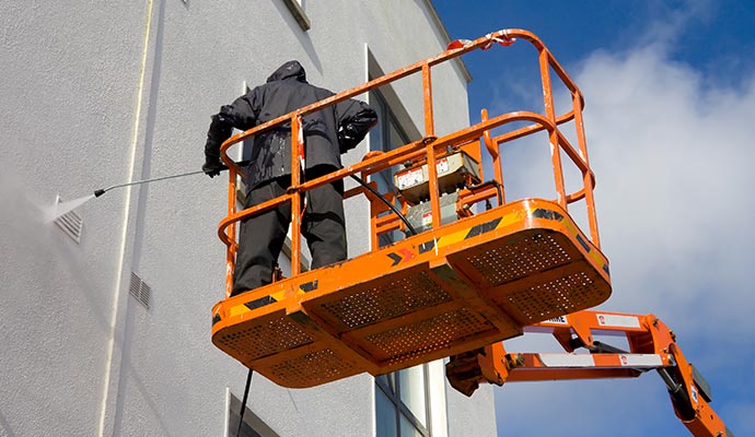 Person pressure washing commercial building