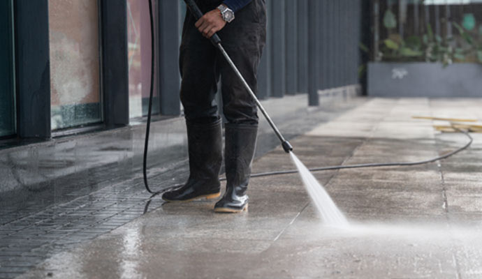 person pressure washing sidewalk