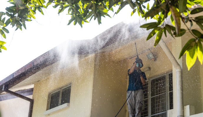 person pressure washing house exterior