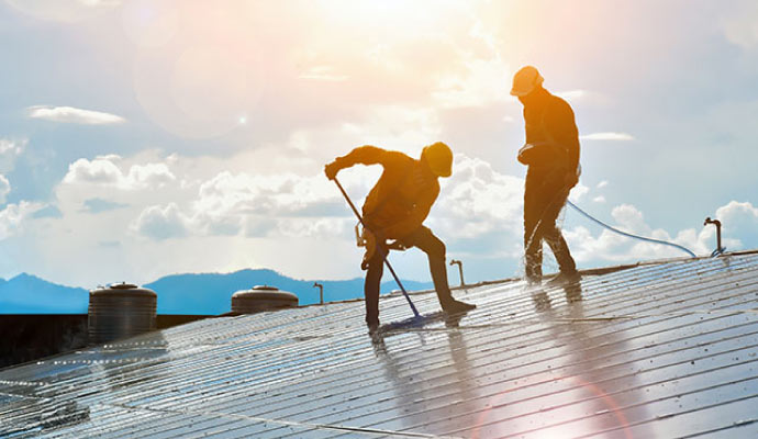 A couple of professionals soft washing a roof