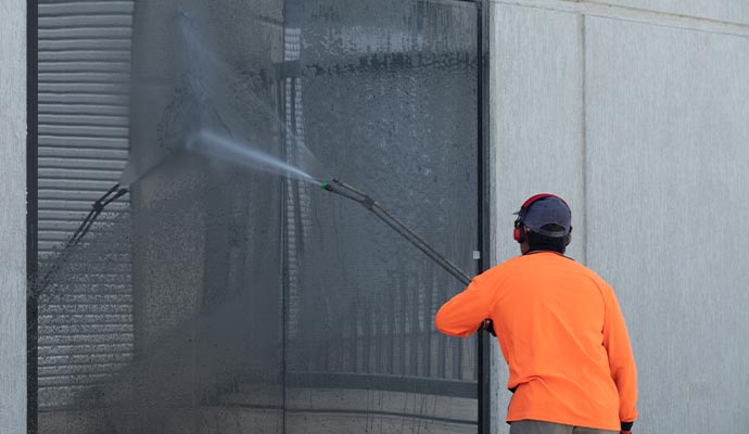 worker pressure washing building exterior