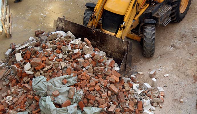 Bulldozer clearing concrete and brick debris at a construction site.