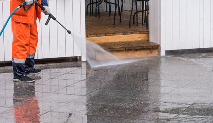 Professional using a pressure washer to clean an outdoor tiled floor