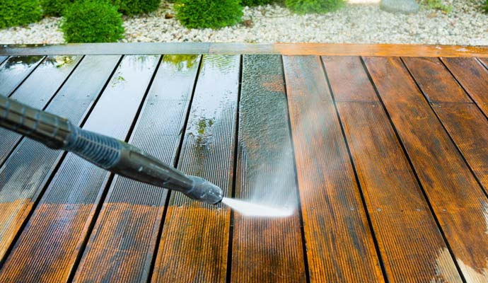 Pressure washing a wooden deck with equipment