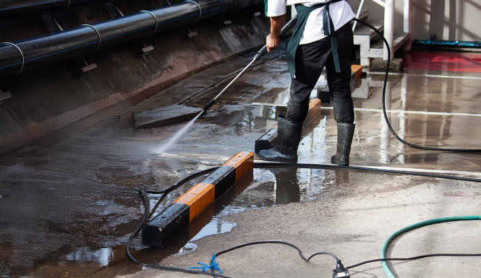 Person cleaning parking lot by pressure washing