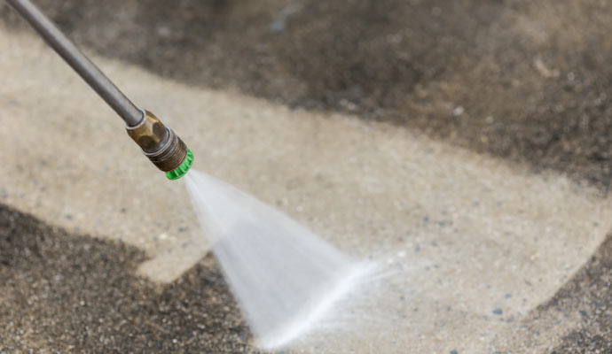 A person pressure-washing pavement using equipment