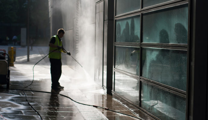 A person cleaning building and its windows using pressure washer