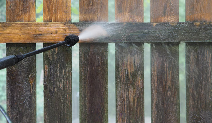 A wooden fence being cleaned with a pressure washer