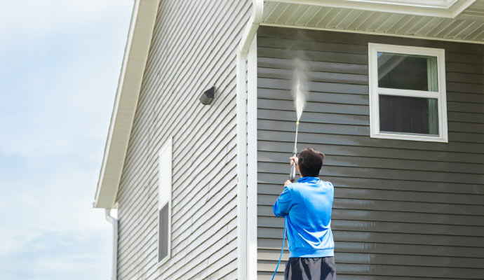 A person cleaning a house using a pressure washer