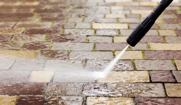 A pressure washer cleaning a paved surface