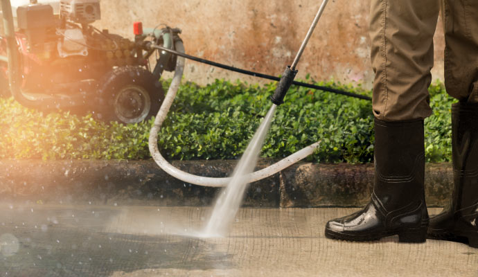 A person cleaning sidewalk using pressure washing machine