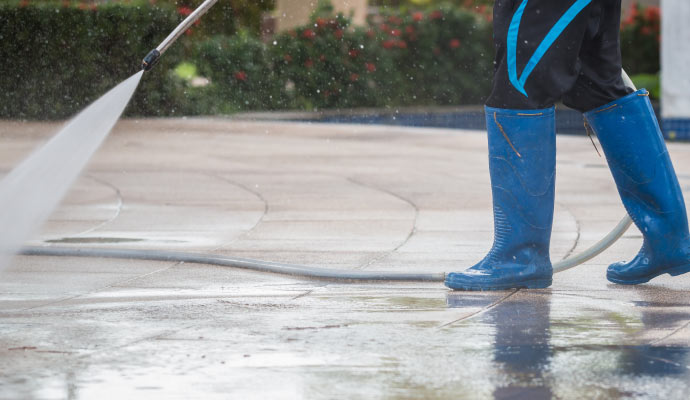 A person cleaning a brick road using a pressure washer