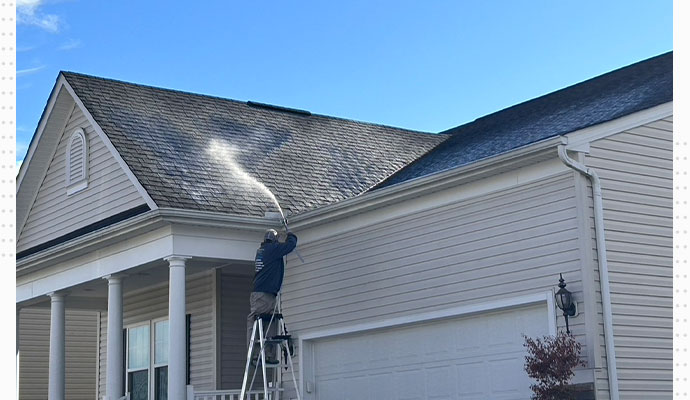 professional worker soft washing residential roof