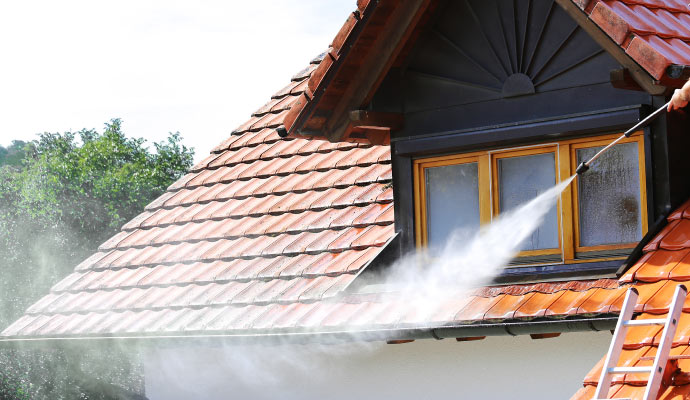 A person using pressure washer to clean roof