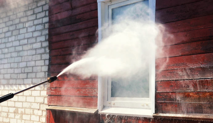 A person using a soft washer to clean a window